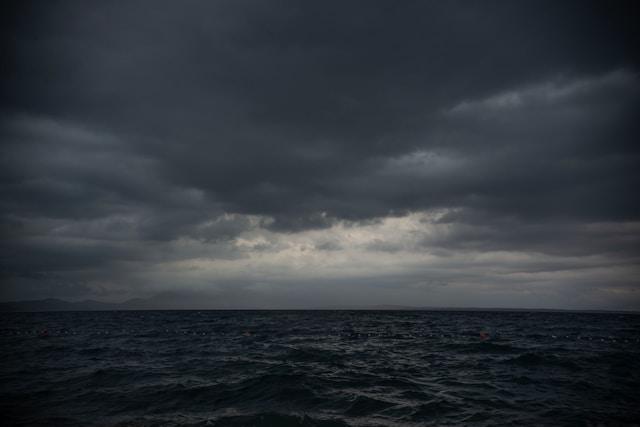A stormy sea beneath dark clouds with a break of light on the horizon, representing the turbulent emotion of grief anger